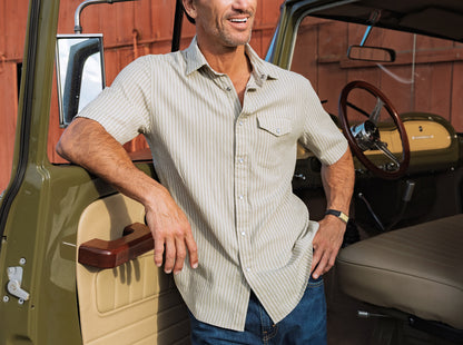 Man standing next to a vintage vehicle with a red barn in the background