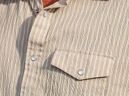 Close-up of a beige seersucker shirt with pearl snap details